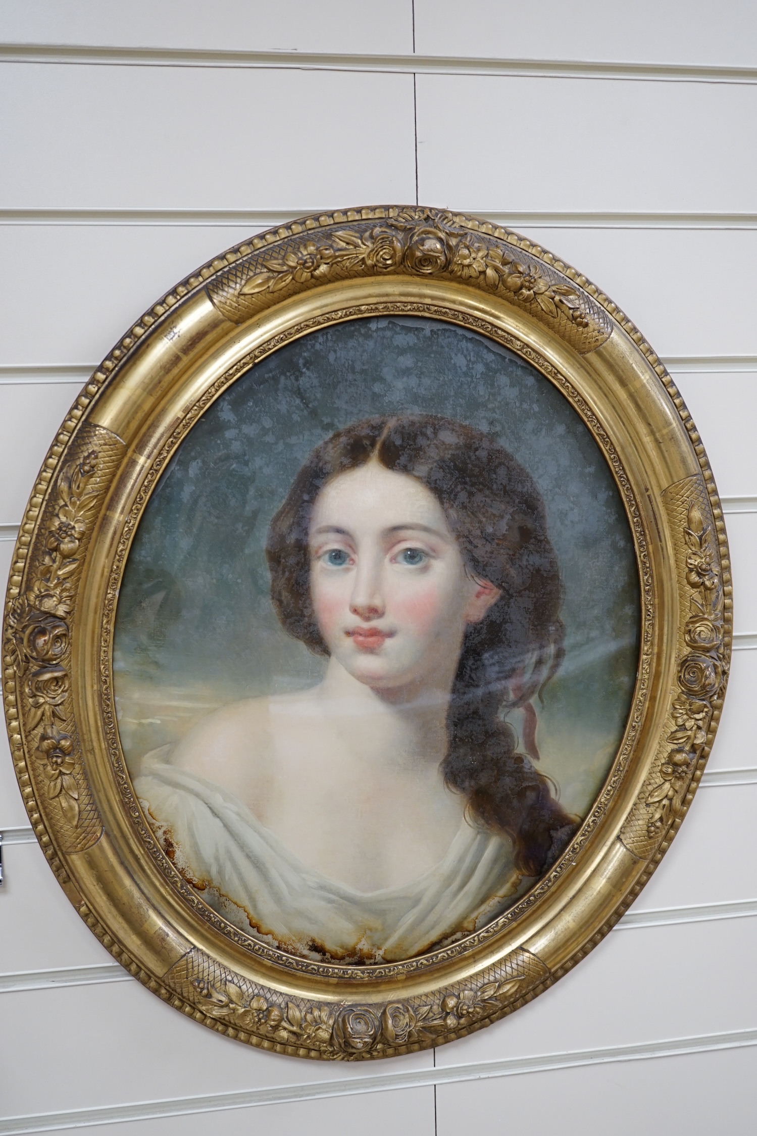 19th century School, reverse glass painted oval panel, Study of a young beauty, 44 x 36cm, housed in a gilt frame. Condition - poor to fair